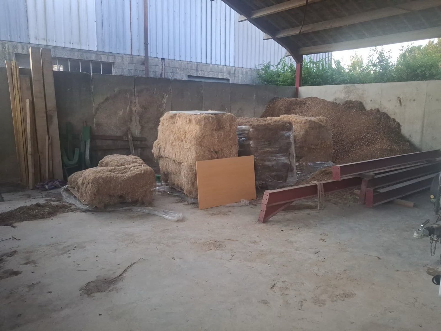 Matières agricoles entreposées sous un hangar avant séchage à basse température